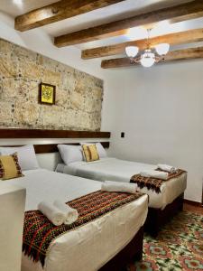 a bedroom with two beds and a stone wall at Hotel Boutique Los Ángeles in Zacatlán