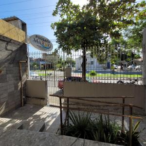 a park bench in front of a fence with a tree at Pousada Maraki in Maceió