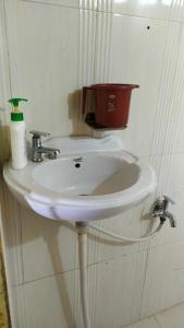 Osiān的住宿－Osian Dhana Ram Ki Dhani Home Stay Osian，白色浴室水槽,墙上装有红色桶