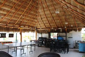 a restaurant with tables and chairs under a straw roof at Hotel & Suites VAYOR in San Patricio Melaque