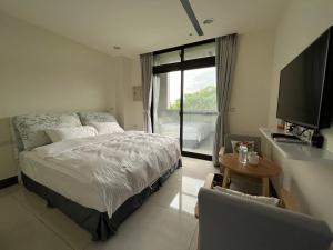 um quarto com uma cama, uma televisão e uma mesa em 金門民宿 x 花藝雅築 The Flower Hut em Jinhu