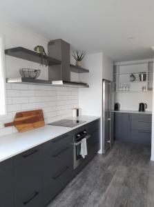uma cozinha com armários cinzentos e uma parede branca em Marsden Cove by the Marina em One Tree Point