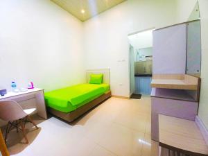 Habitación pequeña con cama verde y escritorio. en Hometown Residence, en Bandar Lampung