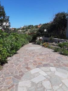a cobblestone walkway in a garden with plants at Appartamento Semi-Interrato Masi in Torre Dei Corsari