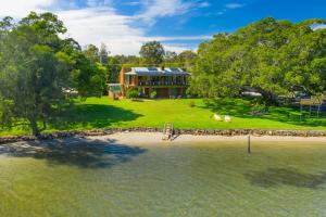 an aerial view of a house on the shore of the water at Punt House - riverfront home with ramp access in Dunbogan