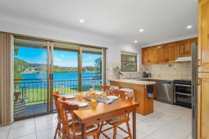a kitchen with a table and chairs and a large window at Punt House - riverfront home with ramp access in Dunbogan
