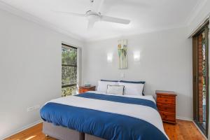 a bedroom with a blue and white bed and a window at Punt House - riverfront home with ramp access in Dunbogan