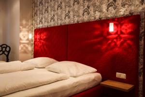 2 Betten in einem Zimmer mit roter Wand in der Unterkunft Altstadthotel Kasererbräu in Salzburg