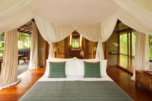 a bedroom with a bed with green and white pillows at COMO Shambhala Estate - CHSE Certified in Payangan