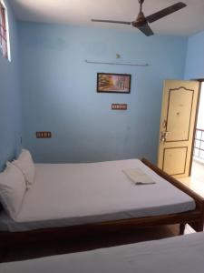 a bedroom with a large bed with a ceiling fan at Parisha Residency- Temple Side Hotel in Chidambaram