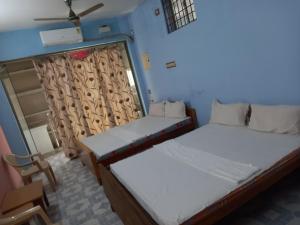two beds in a room with a window at Parisha Residency- Temple Side Hotel in Chidambaram