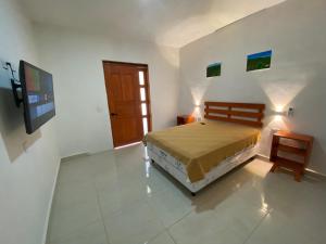 Casa Coronado Izamal في إسامال: غرفة نوم بسرير وتلفزيون بشاشة مسطحة