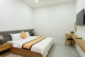 a bedroom with a bed and a desk and a tv at Khang Hy Hotel in Buôn Enao +12 photos