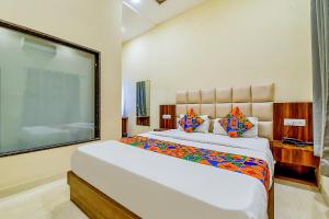 a bedroom with a large white bed with colorful pillows at FabExpress Dosa Plaza in Udaipur