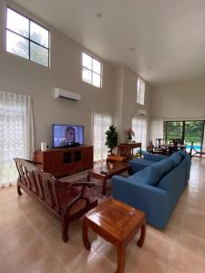 a living room with a blue couch and a tv at Villa Teratai 878 @ A'Famosa Resort in Kampong Alor Gajah