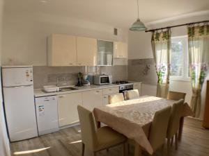 una cocina con mesa y sillas y una cocina con electrodomésticos blancos. en Apartments by the sea Lun, Pag - 9395 en Lun