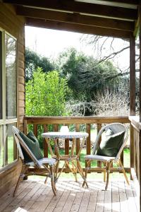 a patio with two chairs and a table on a porch at Drumreagh Cabins in Deloraine