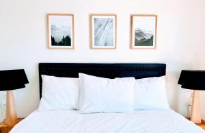 een slaapkamer met een wit bed met drie foto's aan de muur bij Apartment Del Sol Elysée 4 Crans Montana Switzerland in Crans-Montana