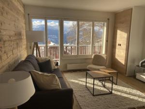 uma sala de estar com um sofá e uma grande janela em Apartment Del Sol Elysée 4 Crans Montana Switzerland em Crans-Montana
