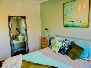 a bedroom with a bed and a large mirror at A Little Bit Beachy Modern Guest Room and Private Toilet in Christchurch