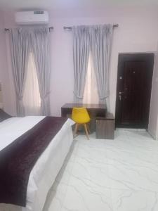 een slaapkamer met een bed en een gele stoel bij Captivating 1-Bed Studio in Sapele in Sapele