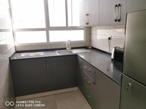 a small kitchen with a sink and a refrigerator at Amazing 2BR pent house flat with mountain view in Muscat
