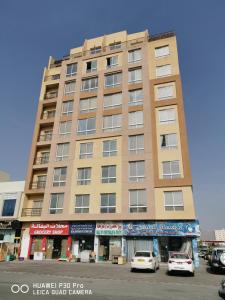 a tall building with cars parked in front of it at Amazing 2BR pent house flat with mountain view in Muscat
