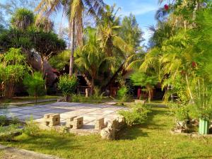 un jardín con palmeras y un camino de piedra en DEA Gili Cottages, en Gili Meno