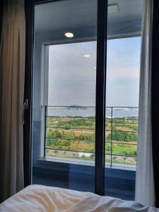 een slaapkamer met een groot raam met uitzicht op de oceaan bij Incheon Rivieraverium Hotel in Incheon