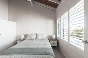 a white bedroom with a bed and a window at Pippi Beach Apartment in Yamba