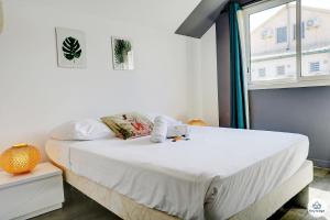 - une chambre avec un lit doté de draps blancs et une fenêtre dans l'établissement T2 - Les Veloutiers - La Saline-les-Bains, à La Saline les Bains