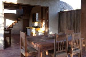 a dining room with a wooden table and a kitchen at Rumah Tinggi at Pachamama in Nembrala