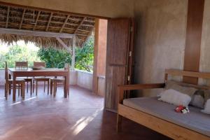 1 dormitorio con mesa, 1 cama y comedor en Rumah Tinggi at Pachamama, en Nembrala
