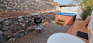 a stone wall with a table and a stool at Casa Geminis, Relax, Sol y Jacuzzi in Tarajalejo