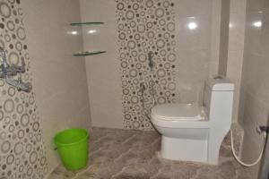 a bathroom with a toilet and a green bucket at Hotel KDISSON in Mohaniā