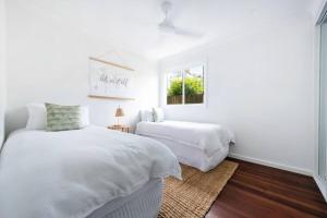 扬巴BAY PROPERTIES . Zephyr的一间带两张床和一扇窗户的白色卧室