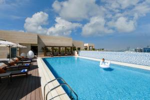 a swimming pool with a person in a raft in a inflatableermott at Le Mirage Downtown in Doha