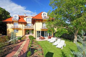 a large yellow house with white chairs in the yard at Balazs Villa in Balatonfüred