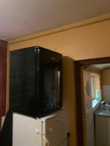 a large black cabinet on top of a refrigerator at Budget house with wifi and parking close to amenities in Burton upon Trent