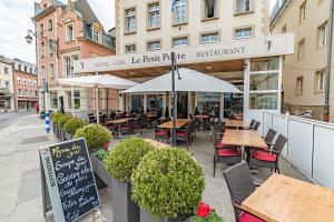 un restaurant avec des tables, des chaises et un parasol dans l'établissement Hôtel Le Petit Poète, à Echternach