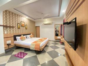 Hotel Gomti Dwarka في دواركا: غرفة نوم بسرير وتلفزيون بشاشة مسطحة