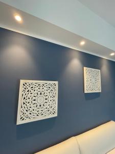dos pinturas en una pared azul con un sofá en Luxury Sea House, en Trapani