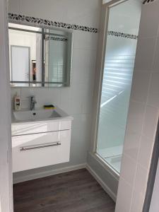 ein weißes Bad mit einem Waschbecken und einer Dusche in der Unterkunft Trés belle suite prés mer et golf avec piscine in Saint-Côme