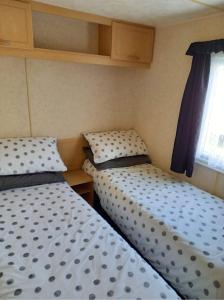 two beds in a small room with a window at Caravan on Golden Palm MV24 Chapel St Leonards in Chapel Saint Leonards