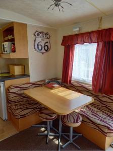 チャペル・セント・レオナルズにあるCaravan on Golden Palm MV24 Chapel St Leonardsのベッド、木製のテーブルと椅子が備わる客室です。