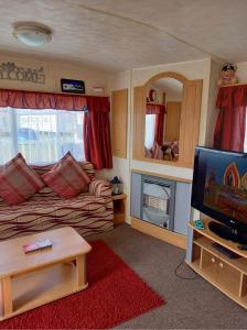 a living room with a couch and a tv at Caravan on Golden Palm MV24 Chapel St Leonards in Chapel Saint Leonards