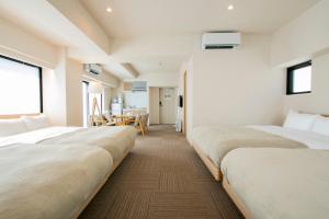 a hotel room with three beds and a table at Ostay Ueno in Tokyo