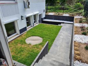 a backyard with a lawn and a walkway at Exklusive Neubau Wohnung im Luftkurort Buchholz in Buchholz in der Nordheide