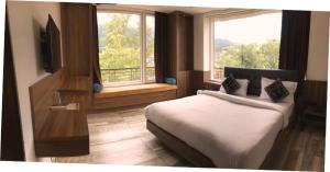 a bedroom with a bed and a large window at Hotel Trihari in Rishīkesh +64 photos