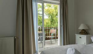 a bedroom with a bed and a balcony with a sliding glass door at Pension zur Regatta in Brandenburg an der Havel